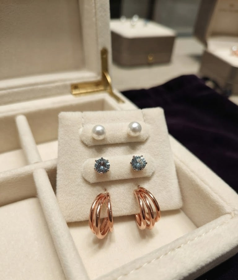 Curated 3-pair earring set with rose gold triple hoops, pearl studs and blue CZ studs on a wooden tray with gift card – AureliaBlends