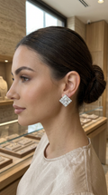 A woman in profile wearing a sparkling square diamond stud earring in a jewelry store.