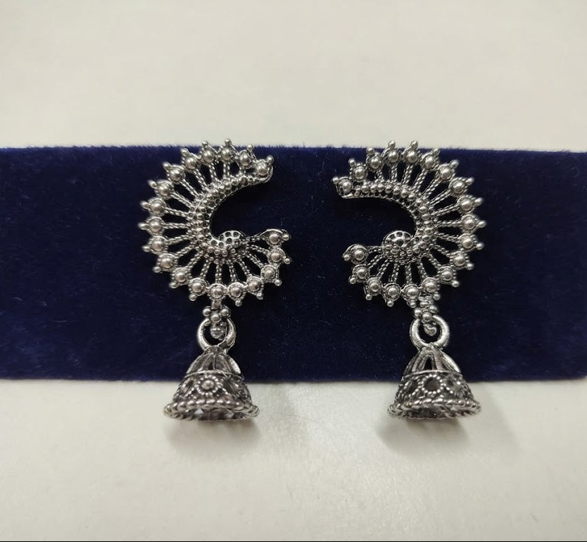 Single pair of oxidized silver crescent peacock jhumka earrings on navy blue velvet – close-up of filigree fan top and jhumka bell drop AureliaBlends
