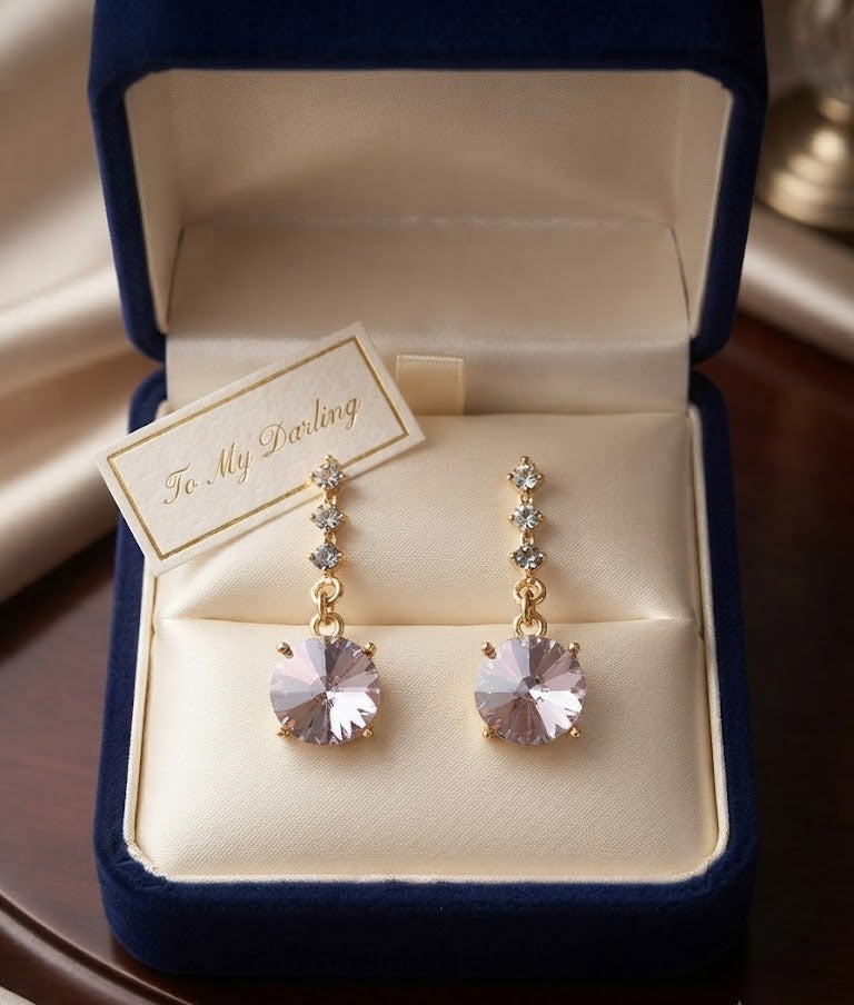 Close-up of gold CZ chain drop earrings with large blush mauve rivoli faceted crystal pendant on black velvet – AureliaBlends statement earrings