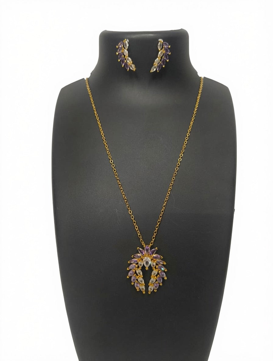 Gold-tone necklace and matching stud earrings displayed on a black jewelry bust against a white background. The pendant and earrings feature purple and yellow stone accents.