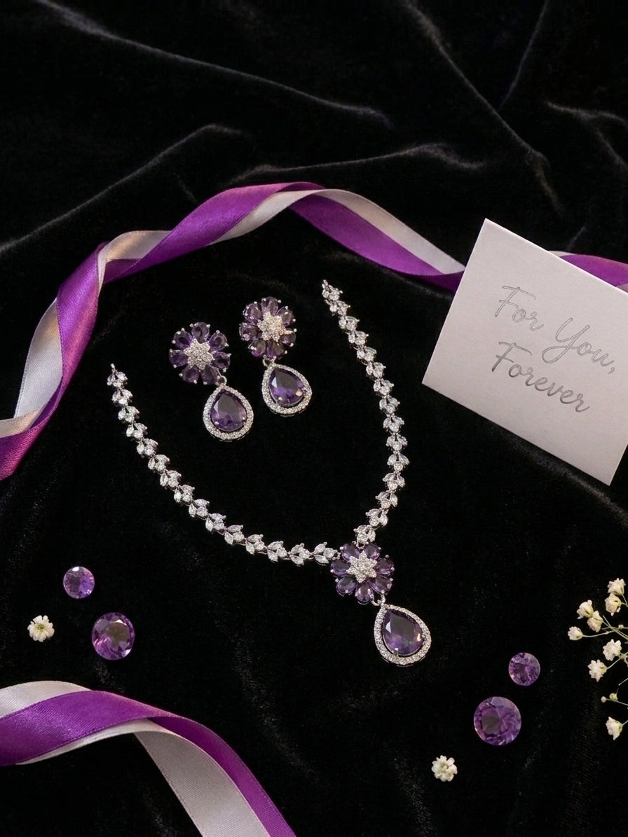 Amethyst purple CZ flower teardrop earrings close-up on black velvet with scattered purple CZ stones – bridal drop earrings by AureliaBlends