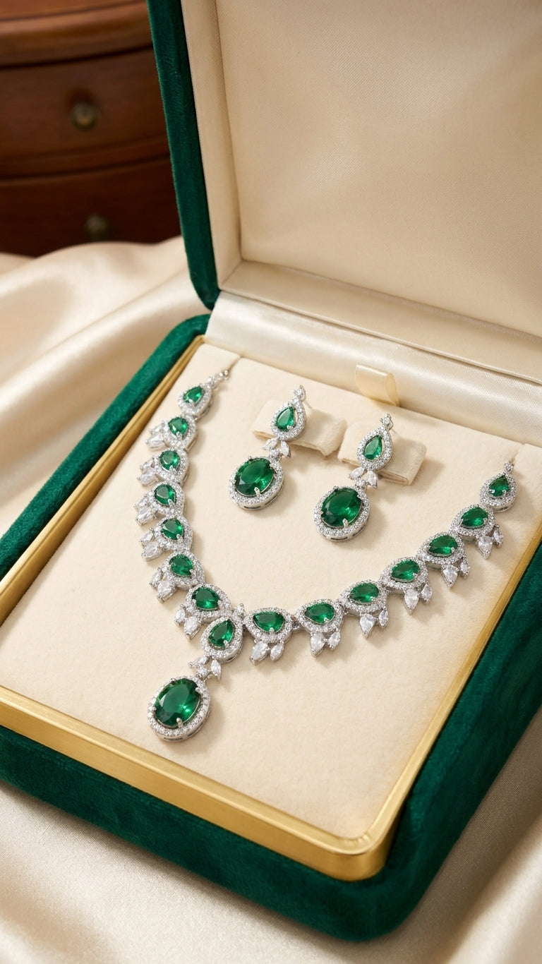 Model wearing emerald green CZ necklace and earrings set with emerald velvet gown under chandelier light – luxury bridal jewelry by AureliaBlends