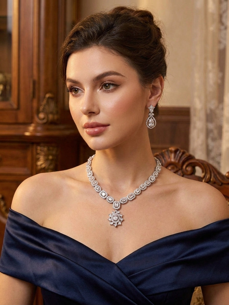Silver cubic zirconia necklace and teardrop earring set displayed in a navy blue velvet jewelry box on a wooden table – AureliaBlends