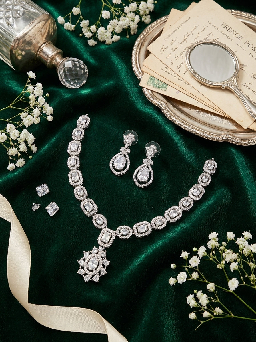 Flat lay of silver CZ statement necklace and matching drop earrings on white background – AureliaBlends bridal jewelry