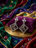 Close-up of oxidised silver pearl trefoil stud and open diamond frame with miniature jhumka bell pendant on black satin with black and silver pearls – AureliaBlends statement earrings