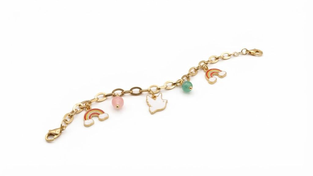 Gold-plated rainbow charm bracelet flat lay on cream silk showing enamel rainbow, dove and gemstone bead charms – AureliaBlends