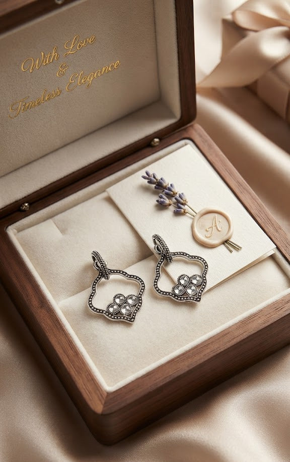 AureliaBlends oxidised silver quatrefoil pearl cluster drop earrings editorial flat lay on cream linen with walnut wood jewellery box and silver accessories