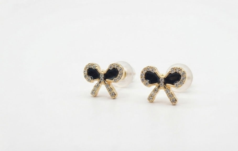 Gold pavé CZ black bow stud earrings displayed in an open cream velvet luxury jewellery box with gold monogram lid on a dark wood surface – AureliaBlends Timeless Elegance Collection