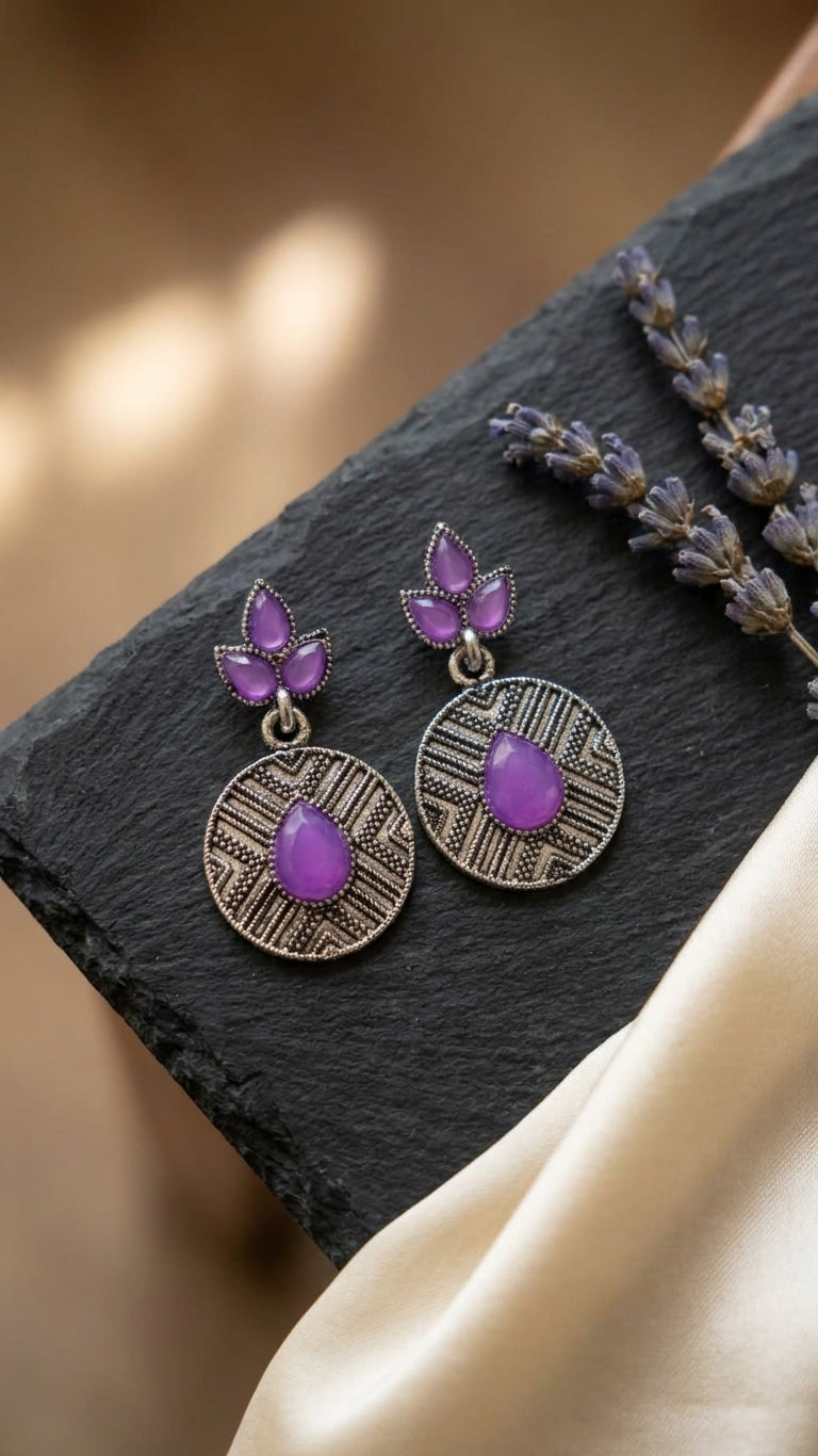 Oxidised silver marquise leaf and engraved disc drop earrings with emerald green stones lifestyle flat lay on wooden surface with eucalyptus and white fabric – AureliaBlends