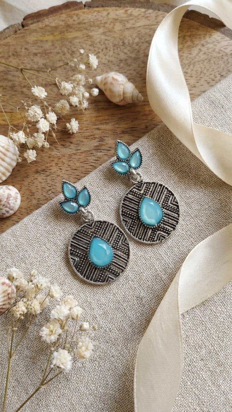 Oxidised silver marquise leaf and engraved disc drop earrings with turquoise blue stones on wooden tray with dried flowers and cream ribbon – AureliaBlends boho ethnic earrings