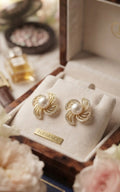 Gold pavé CZ swirl floral pearl stud earrings on a white jewellery card on black velvet background – AureliaBlends Elegance Collection product shot