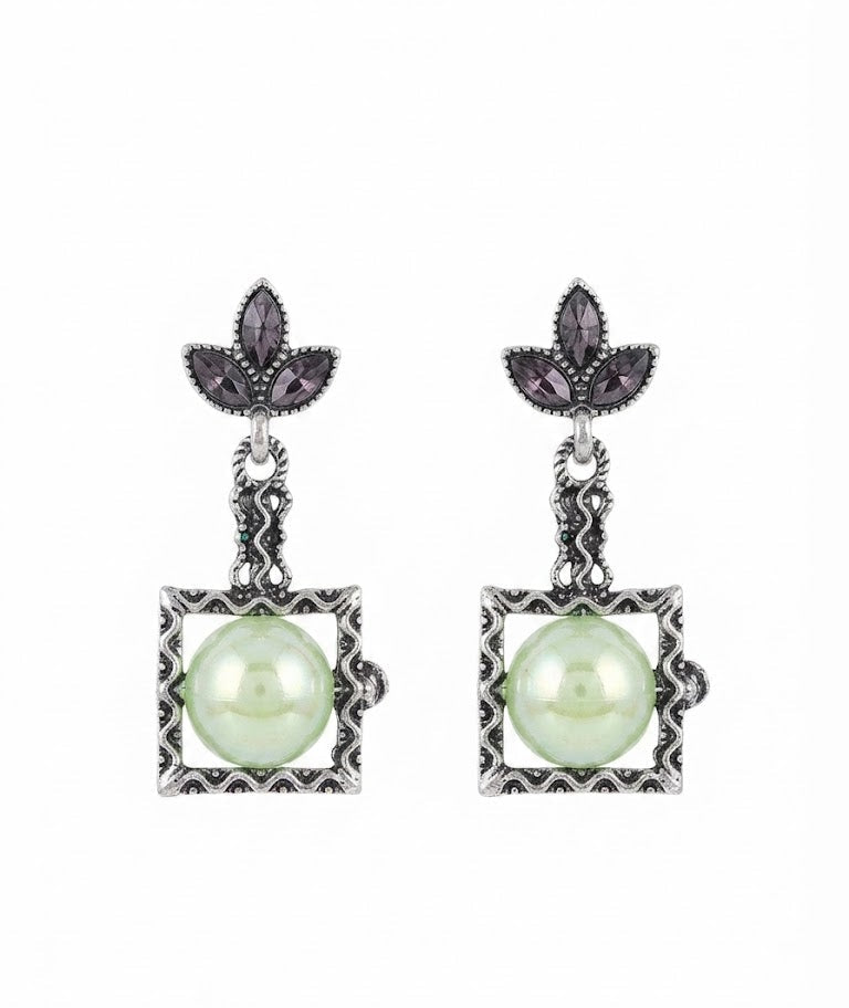 Model with elegant low chignon bun wearing oxidised silver marcasite fleur-de-lis leaf stud and square pearl cabochon drop earrings in cream ivory – AureliaBlends vintage dangle earrings