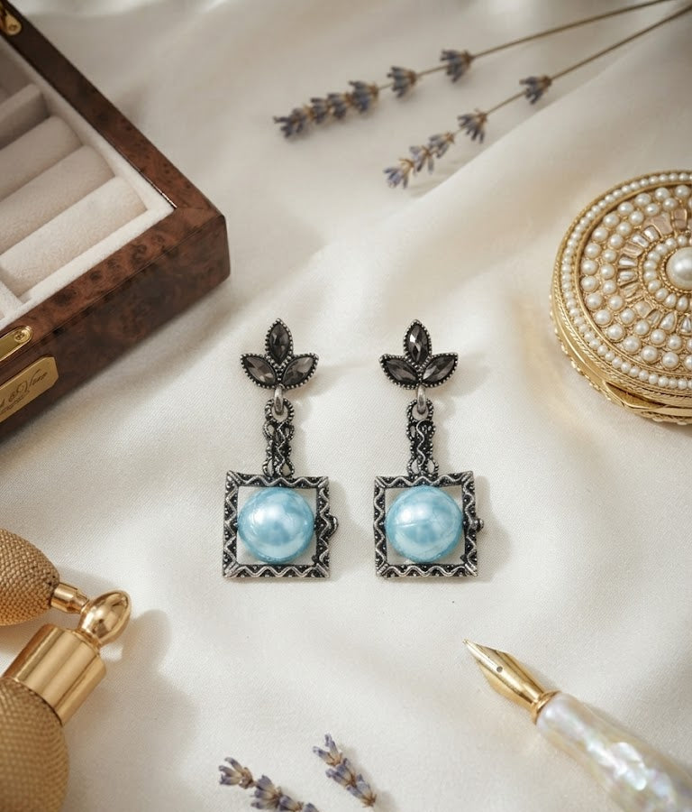 Oxidised silver marcasite leaf and square cream pearl drop earrings in open burl walnut wood gift box with cream velvet lining on black background with scattered multicolour gemstones – AureliaBlends statement earrings