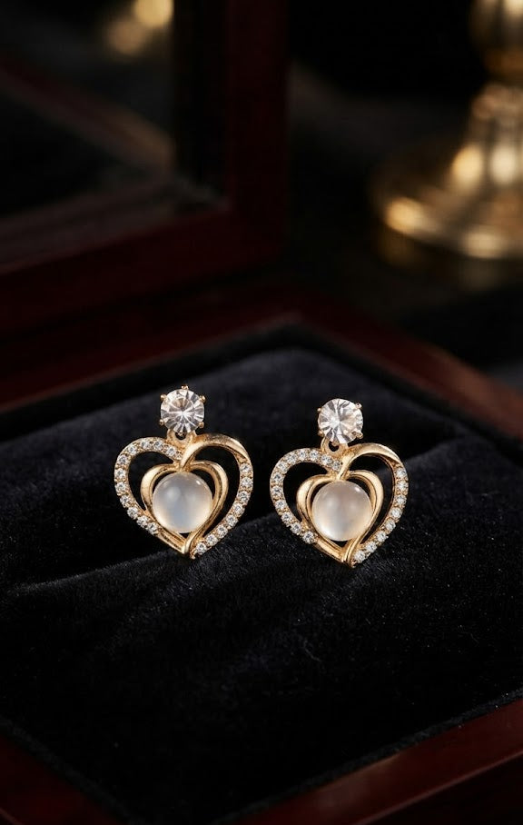 Gold CZ open heart moonstone drop earrings in an open dark walnut jewellery box with a gold heart necklace and champagne glass in the background on ivory satin – AureliaBlends bridal jewellery