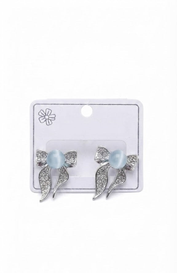 Silver pavé CZ moonstone bow stud earrings in an open navy blue velvet jewellery box on a grey surface with a second closed navy box in the foreground – AureliaBlends