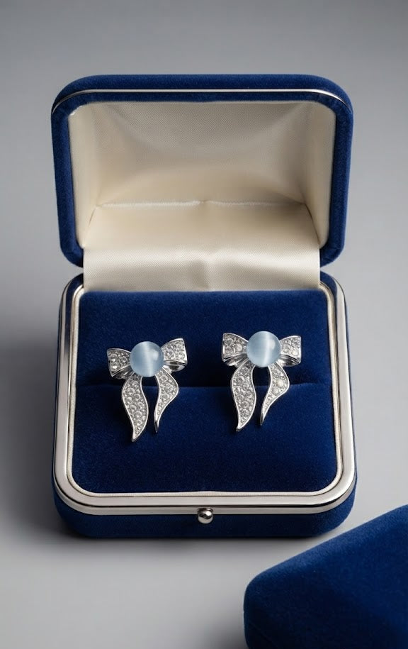 Model wearing silver pavé CZ moonstone bow stud earrings with a sleek low bun – side profile close-up on grey background – AureliaBlends romantic bridal earrings