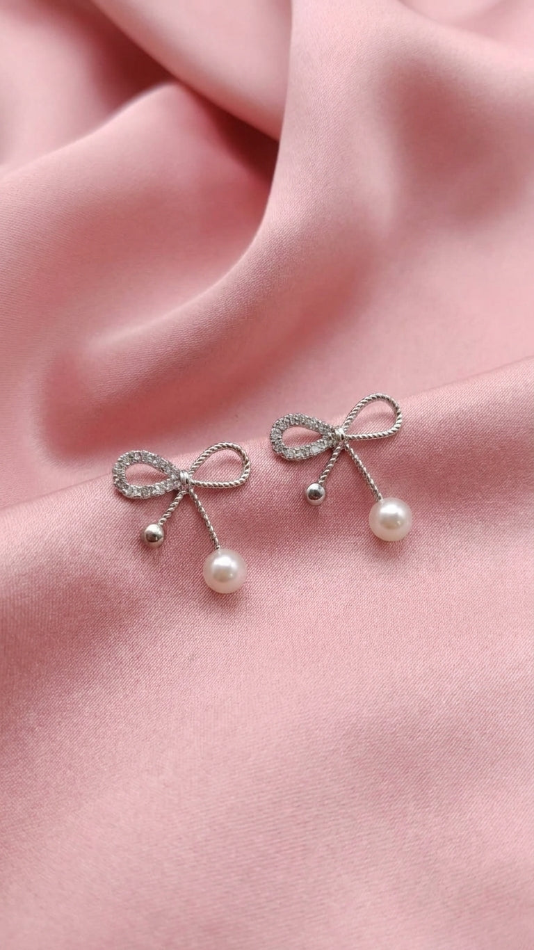 Silver CZ twisted rope bow pearl drop earrings on black velvet fabric – AureliaBlends statement dangle earrings dark editorial shot