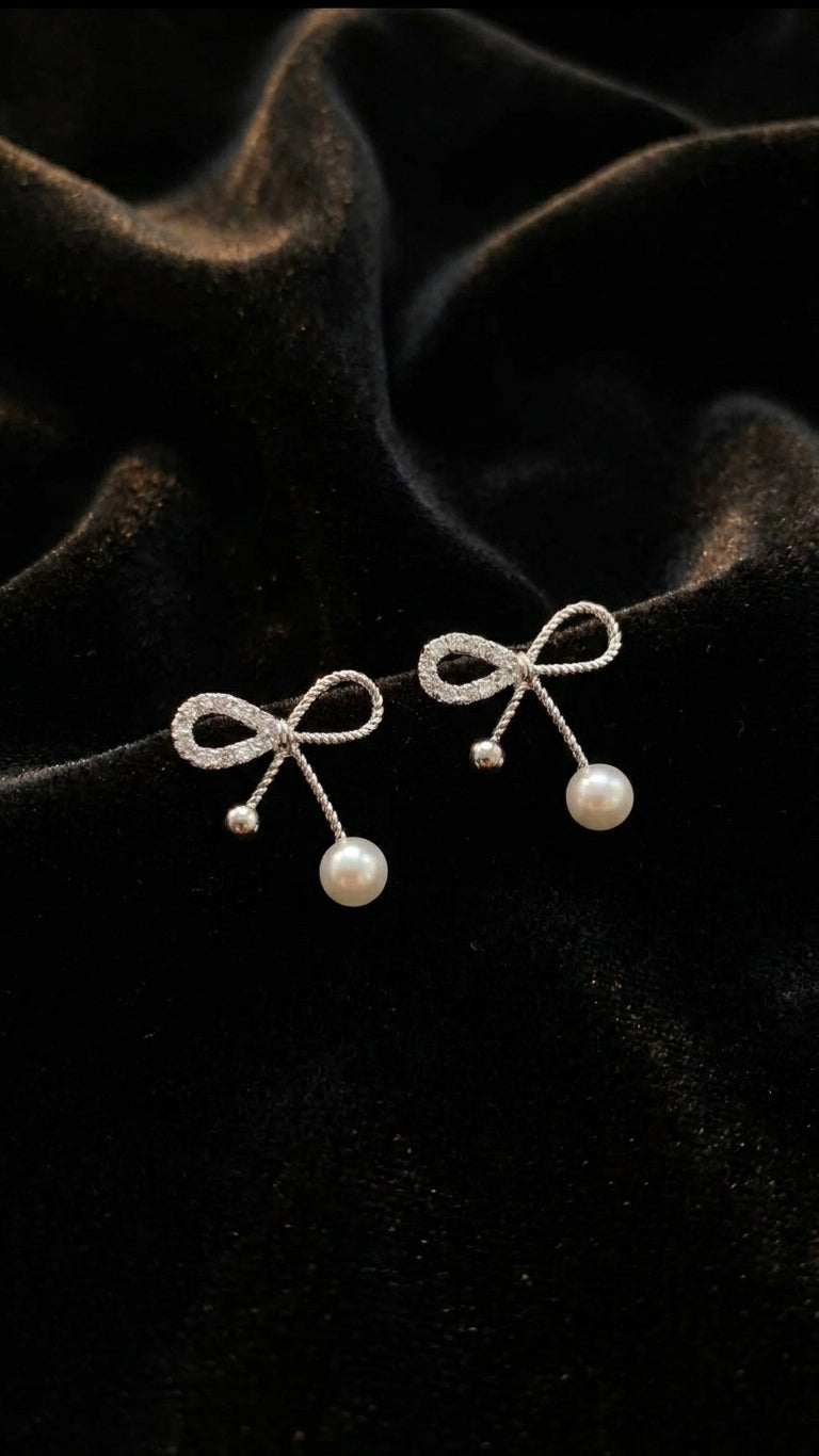 Silver CZ twisted bow pearl drop earrings close-up product shot on white background showing twisted rope bow detail and pearl drops – AureliaBlends dainty bridal earrings