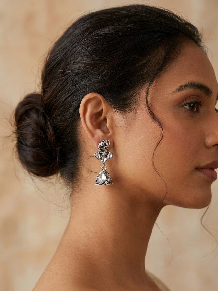 Oxidised silver peacock CZ kundan and jhumka bell drop earrings editorial flat lay on white marble with lavender sprigs, blue satin ribbon, blush velvet ring boxes, pearl necklace and antique silver rings – AureliaBlends