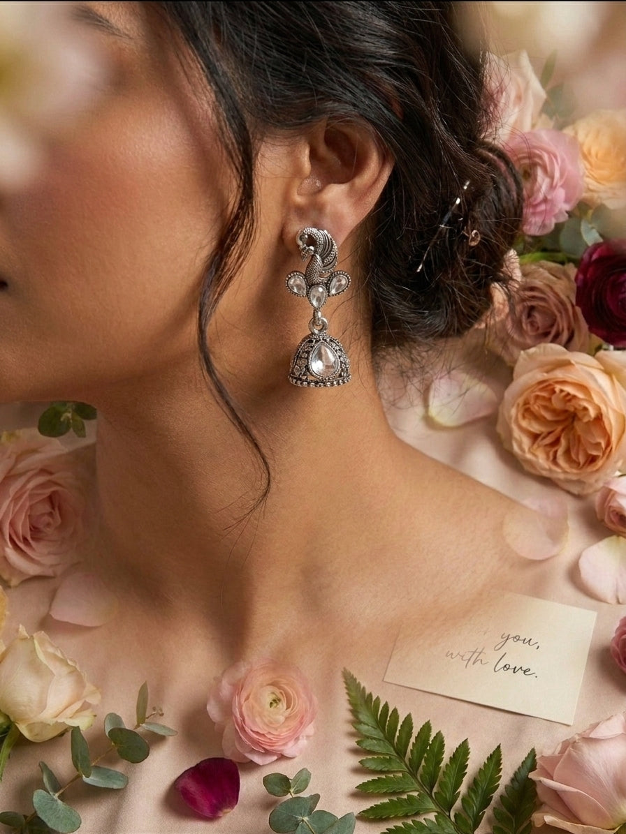 AureliaBlends oxidised silver peacock CZ kundan trefoil and jhumka bell drop earrings lifestyle editorial flat lay on white marble with lavender, pearl necklace, blush velvet ring boxes and blue satin ribbon