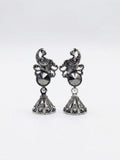 Oxidised silver peacock scroll filigree and hematite rivoli jhumka bell drop earrings flat lay on white marble with scattered black pearls, dried cream buds, antique silver trinket box and blue silk saree – AureliaBlends ethnic earrings