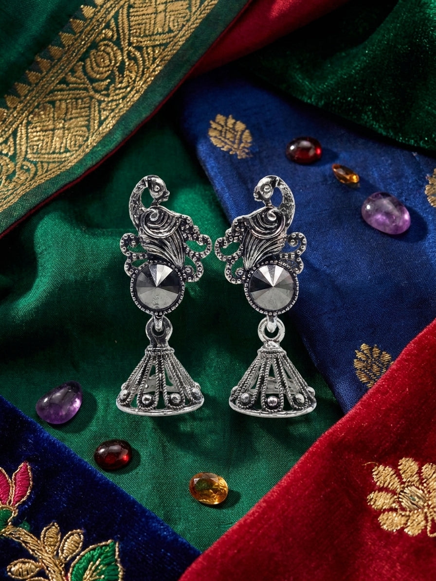Oxidised silver peacock scroll and hematite rivoli jhumka bell drop earrings surrounded by blush pink roses gypsophila and eucalyptus on soft pink background – AureliaBlends romantic ethnic earrings