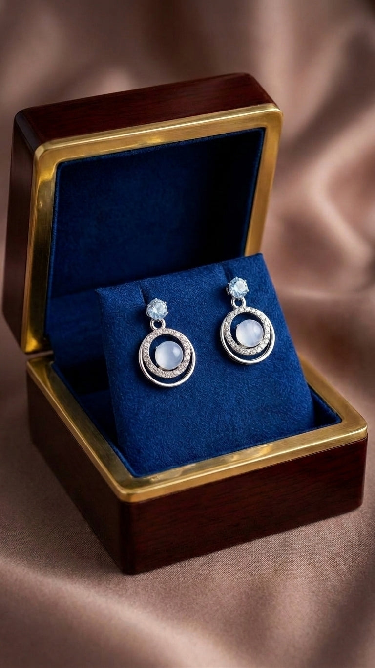 Silver aquamarine CZ double orbit moonstone drop earrings in an open dark walnut jewellery box with navy blue velvet cushion on bronze satin – AureliaBlends luxury bridal earrings
