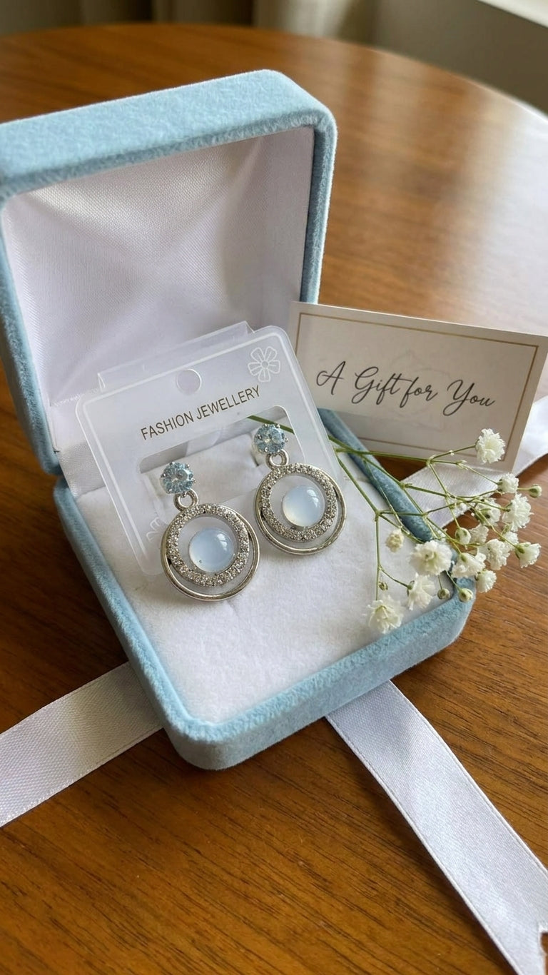 Silver aquamarine CZ double orbit moonstone drop earrings in an open light blue velvet gift box with a 'A Gift for You' card and baby's breath on a wooden table with white satin ribbon – AureliaBlends gift jewellery