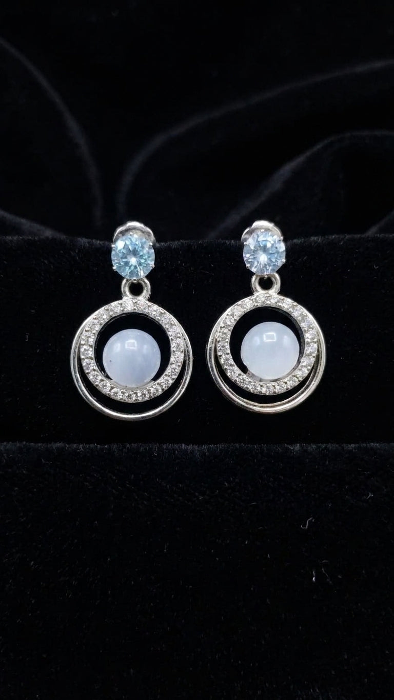 Silver aquamarine CZ double orbit moonstone drop earrings on black velvet background showing double orbit frame, aquamarine CZ stud and blue moonstone cabochon detail – AureliaBlends statement dangle earrings