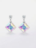 Model wearing silver CZ round solitaire stud and large square aurora borealis iridescent crystal drop earrings in diamond orientation showing rainbow pink purple blue shimmer – AureliaBlends crystal dangle earrings