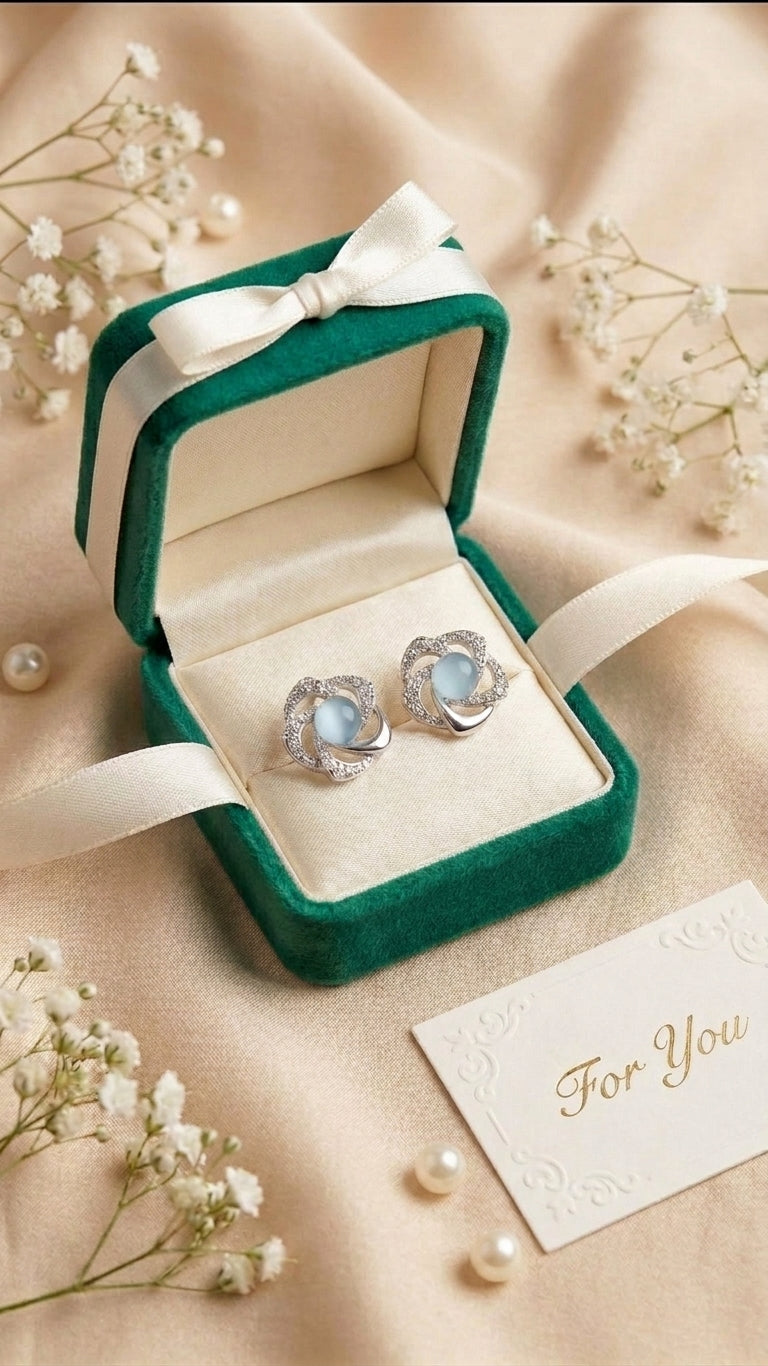 Silver pavé CZ swirl floral moonstone stud earrings flat lay on black satin with baby’s breath, loose pearls and a ‘For You’ card – AureliaBlends dark editorial statement stud earrings