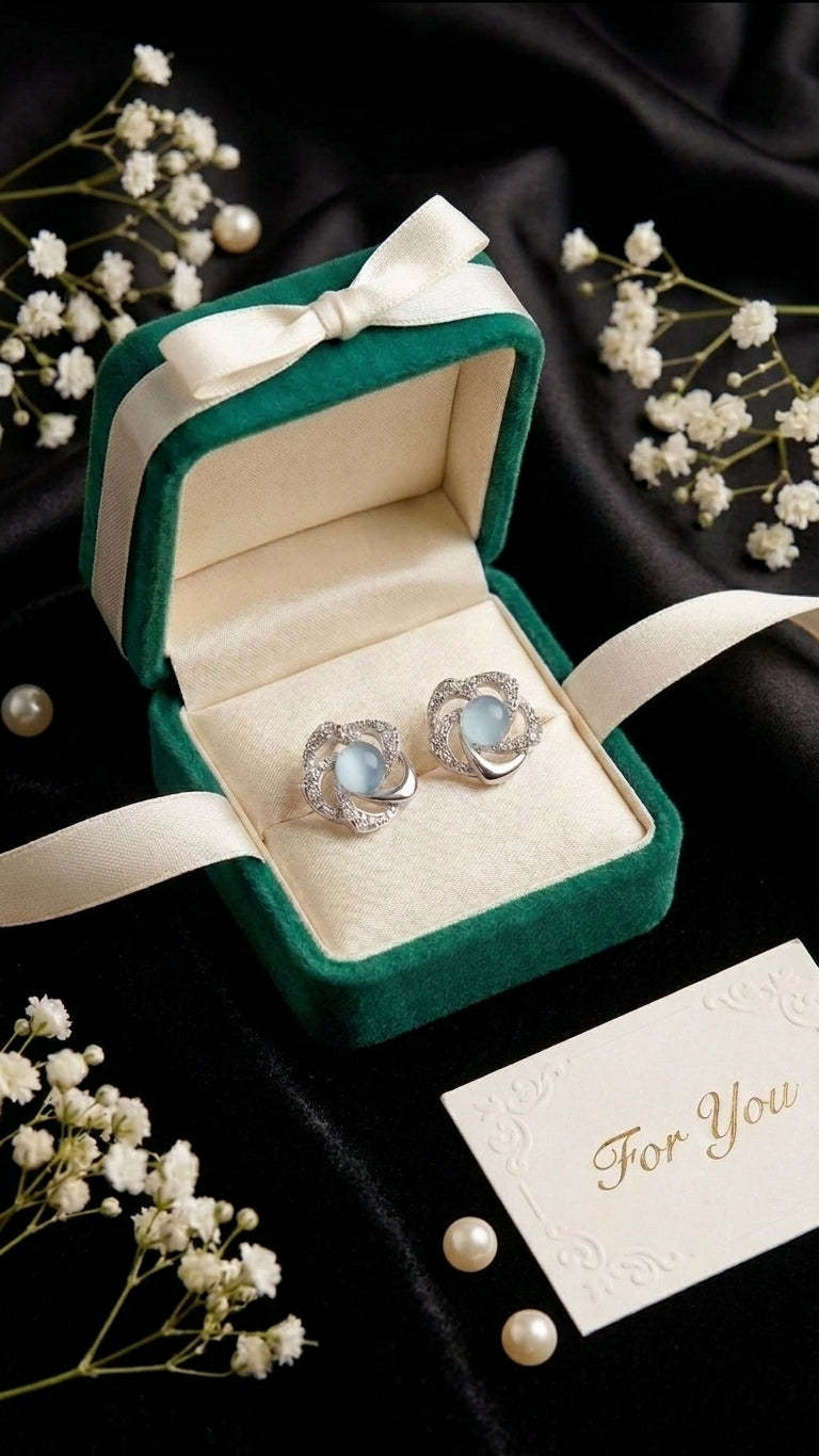 Silver pavé CZ swirl floral moonstone stud earrings close-up on black satin showing swirl petal pavé CZ detail and blue moonstone cabochon centre – AureliaBlends moonstone stud earrings