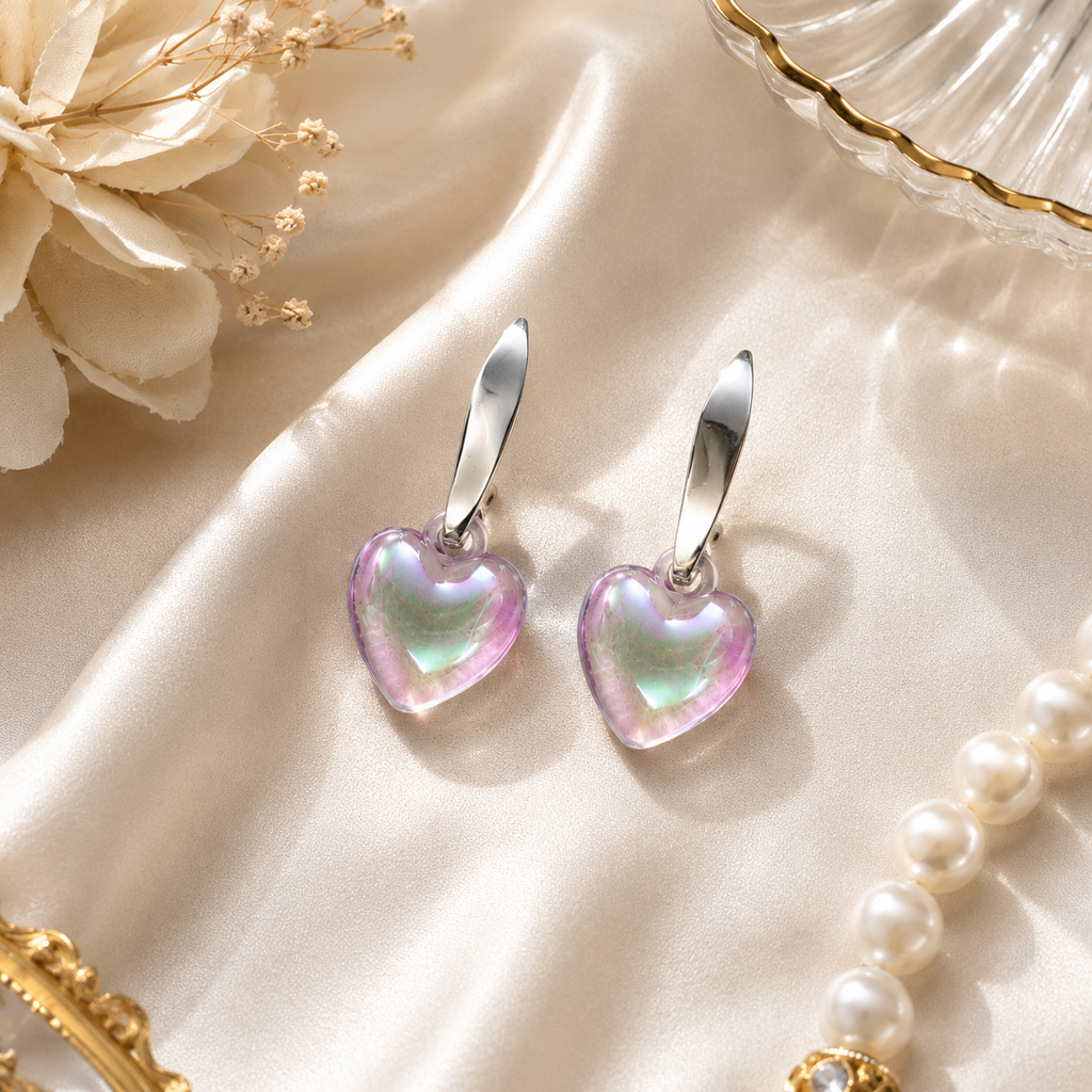 Silver huggie hoop and iridescent aurora heart crystal drop earrings flat lay on black velvet with gold crystal vase, dried gypsophila and gold satin ribbon showing full aurora borealis shimmer – AureliaBlends statement earrings