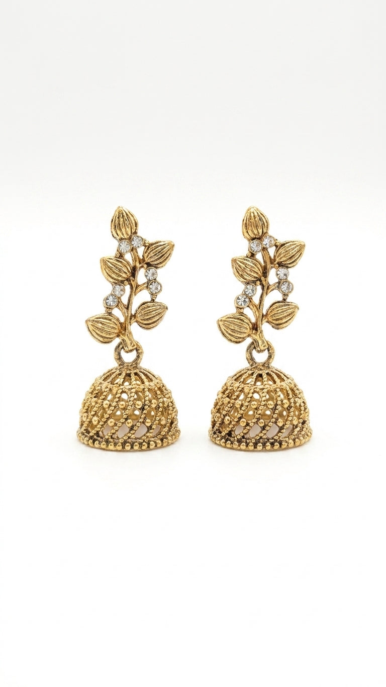 Model in profile wearing gold-plated CZ botanical leaf vine and open filigree dome jhumka bell drop earrings in warm antique gold against dark teal and burgundy background – AureliaBlends Indian wedding earrings