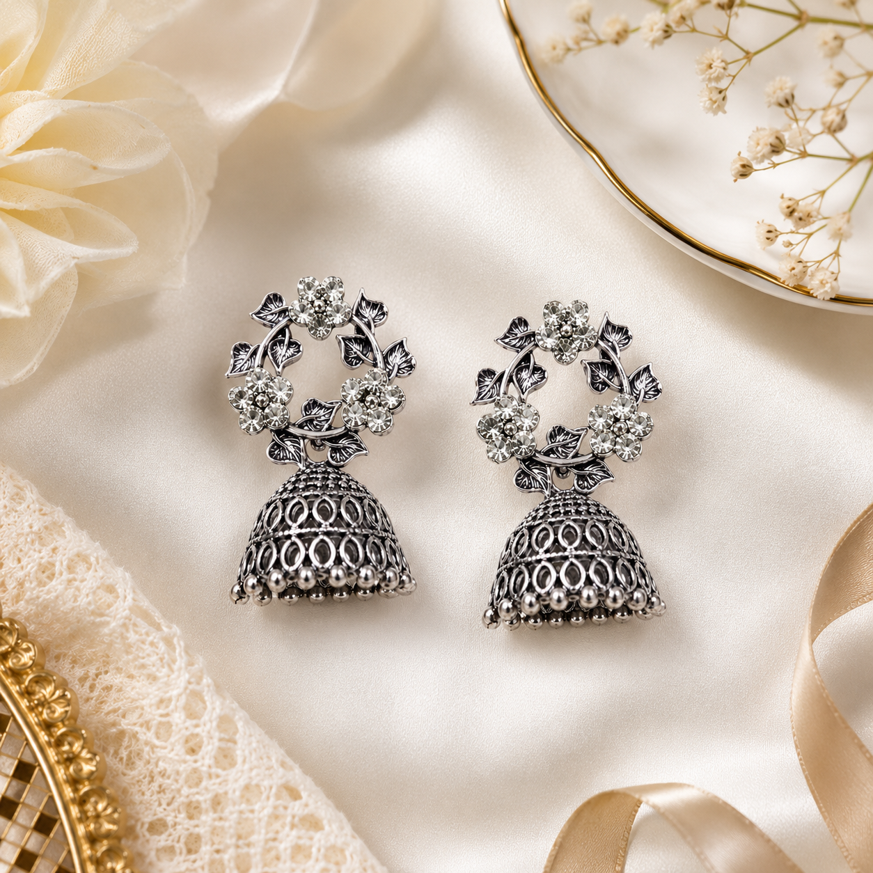 Oxidised silver CZ floral wreath and open oval lattice jhumka bell drop earrings on dramatic black velvet showing full antique silver detail of five CZ flower wreath and interlocking oval lattice jhumka bell with silver ball fringe rim – AureliaBlends statement earrings