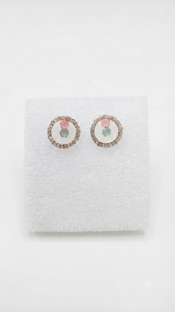 Model wearing rose gold pavé CZ open circle halo pink rose quartz and mint green aventurine stud earrings with a sleek updo at a warm luxury dressing table with a walnut jewellery box and perfume in the background – AureliaBlends