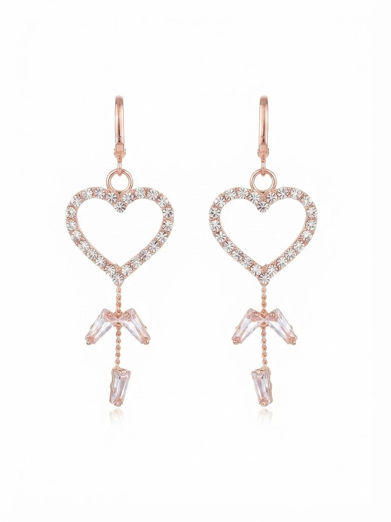 Model wearing rose gold pavé CZ open heart baguette crystal tassel leverback drop earrings with a sleek low chignon in a warm champagne luxury interior with a walnut jewellery box in the background – AureliaBlends bridal earrings side profile