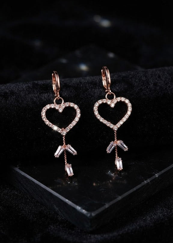 Rose gold pavé CZ open heart baguette crystal tassel leverback drop earrings close-up on dark black velvet showing full pavé CZ open heart frame, rose gold leverback hoop, three chain tassels and baguette crystal drop ends – AureliaBlends heart tassel drop earrings detail shot