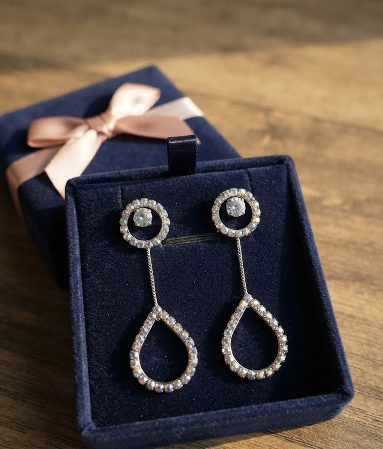 Silver CZ round halo solitaire chain teardrop pavé long drop earrings on a navy blue velvet jewellery cushion surrounded by dusty mauve roses, lavender, baby’s breath and eucalyptus – AureliaBlends romantic floral editorial