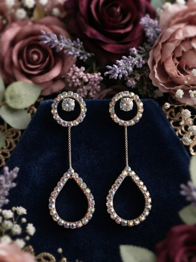 Silver CZ round halo solitaire chain teardrop pavé long drop earrings close-up on navy blue velvet with dusty mauve roses and lavender showing CZ halo stud sparkle and open teardrop pavé frame detail – AureliaBlends bridal dangle earrings