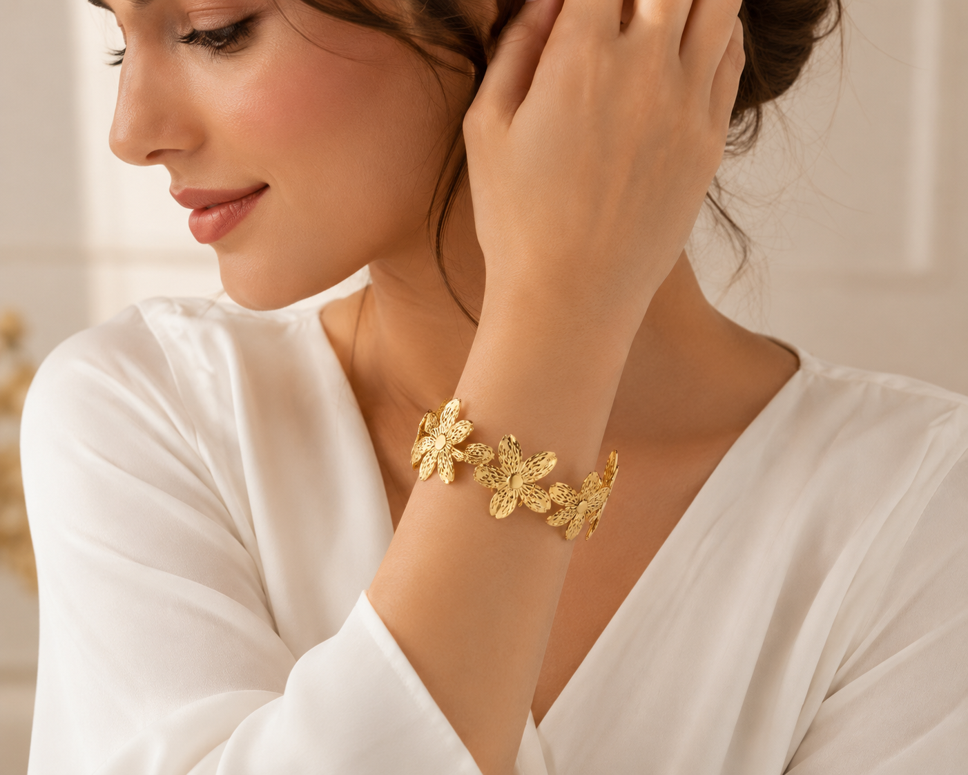 Woman wearing gold hibiscus wide cuff bracelet on wrist in white dress – AureliaBlends statement gold bangle