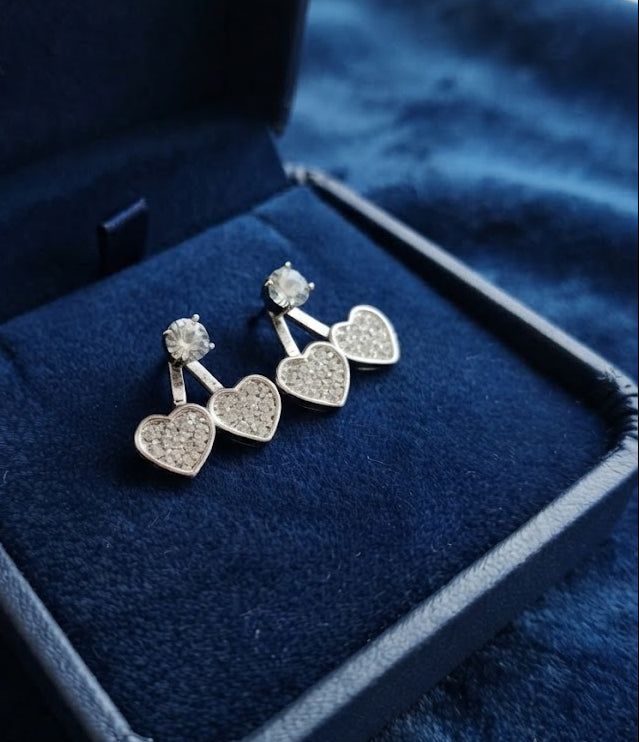 Silver CZ double heart ear jacket earrings worn on model ear showing floating double heart drop effect – AureliaBlends statement earrings